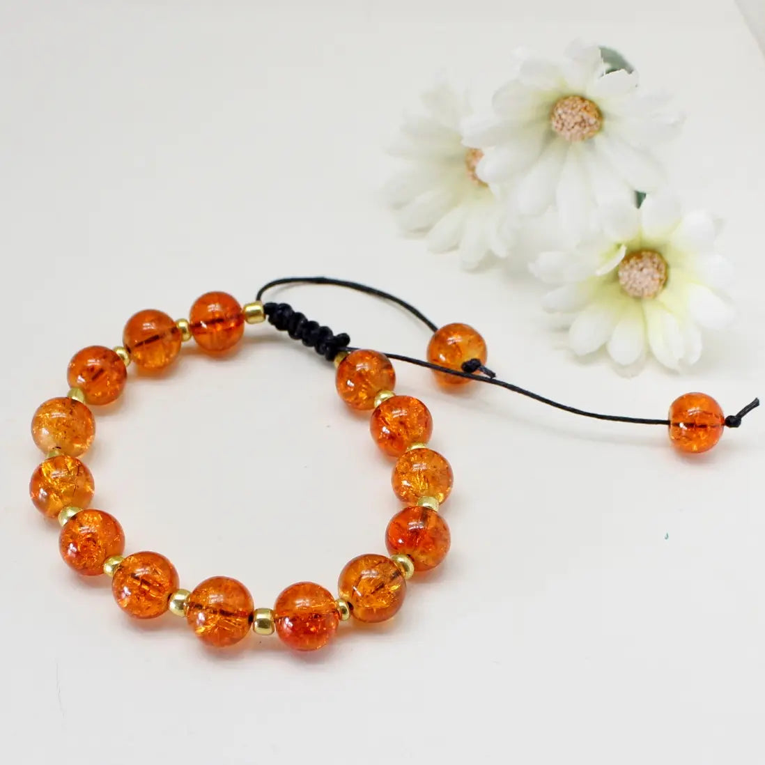 Orange armbånd med makrame lås vist liggende på bord