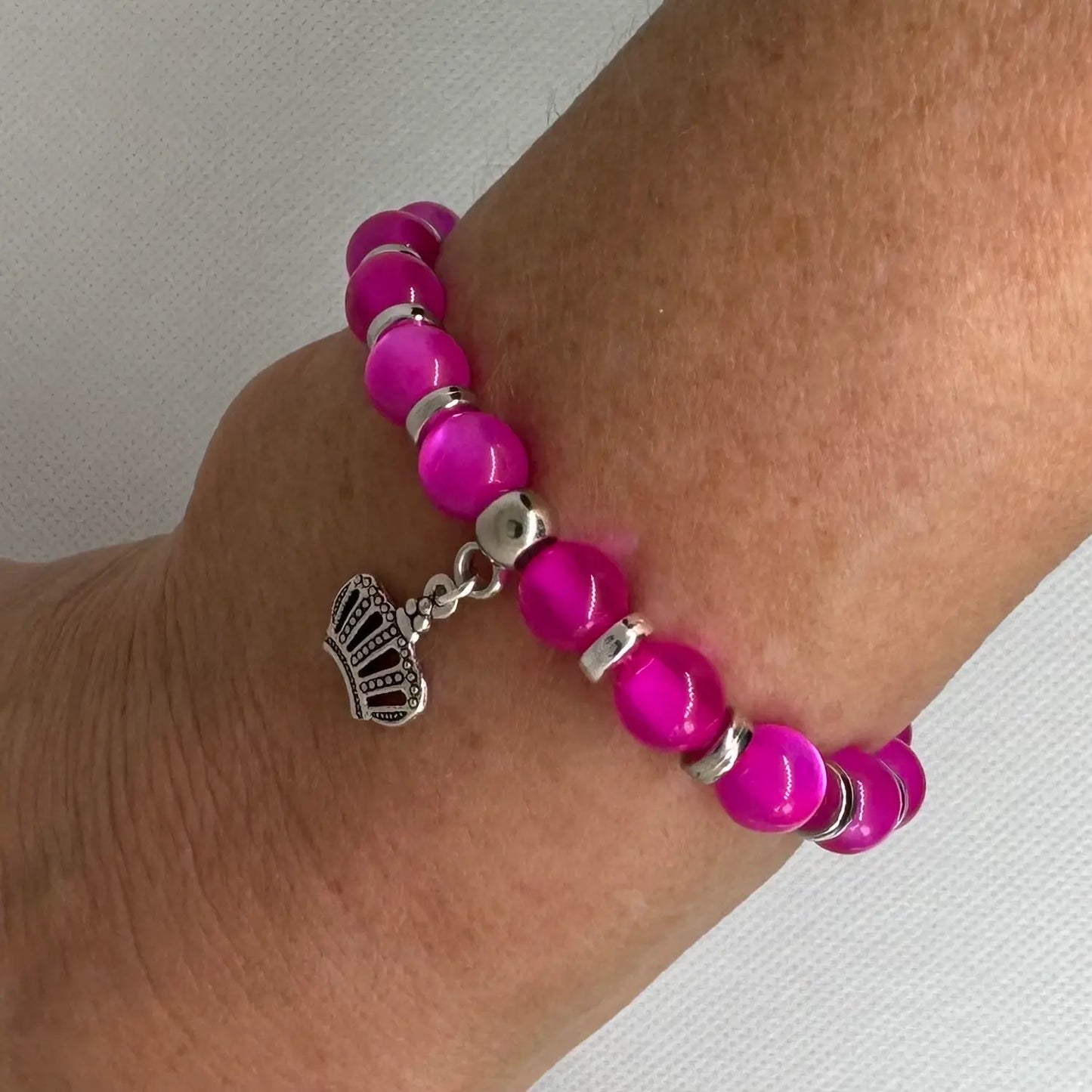 Armbånd i rosa glassperler med anheng, vist på arm