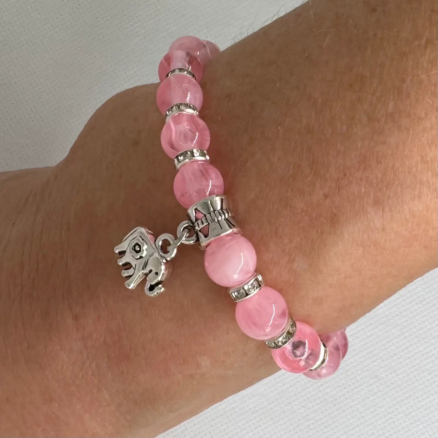 Armbånd i rosa glassperler med elefant, vist på modell