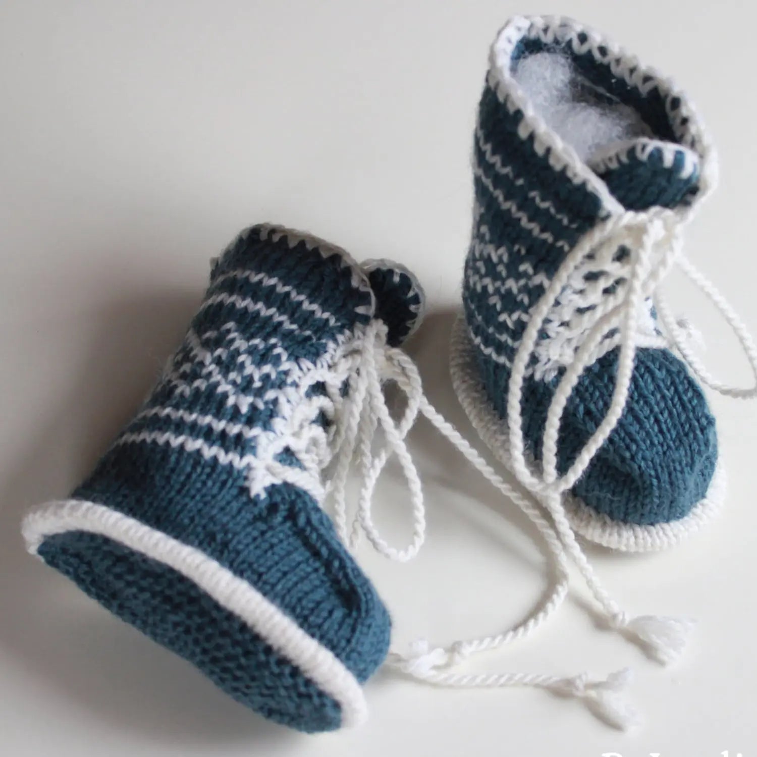 Babybooties med snøring i grønt farge vist stående og liggende for å vise sålen