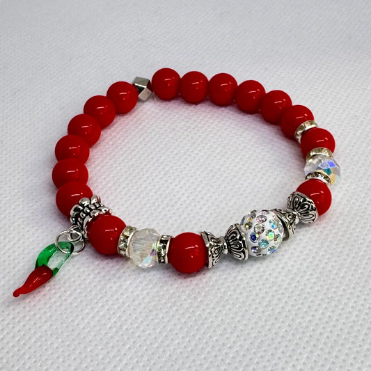 Rødt armbånd med chilli og glitterdetaljer vist liggende på bord