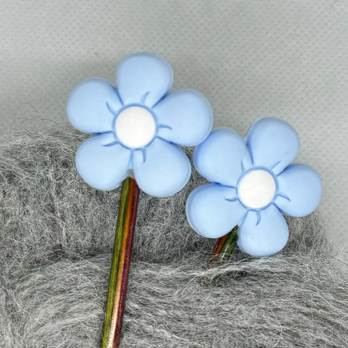 Maskestopper med silikonblomst i lys blå, på pinnene