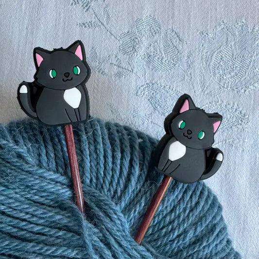 Maskestoppere med sort katt på strikkepinner i garnnøste