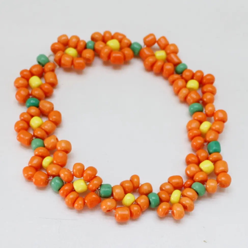 Orange blomsterarmbånd vist liggende på bord