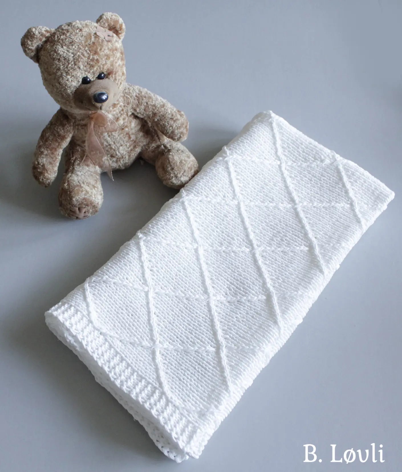 Petit babyteppe strikket med lett strukutmønster