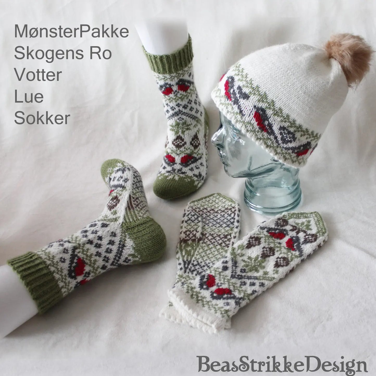 Skogens Ro mønsterpakke vist på modell og liggende, lue, votter og sokker med dompapper på